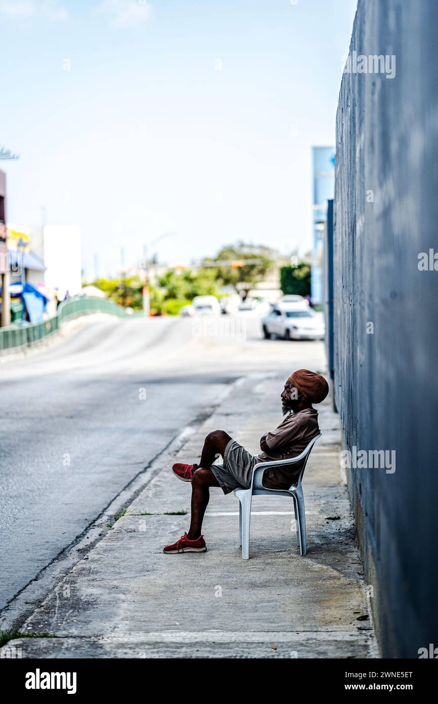 Ein Bajaner sitzt gerade dabei, wie die Welt in Bridgetown, Barbados, vorbeizieht. Stockfoto