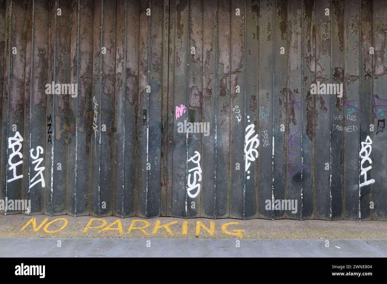 Eine verwitterte industrielle Schiebetür, die mit Graffiti markiert wurde, Hatton Place, London, Großbritannien. 1. Mai 2023 Stockfoto