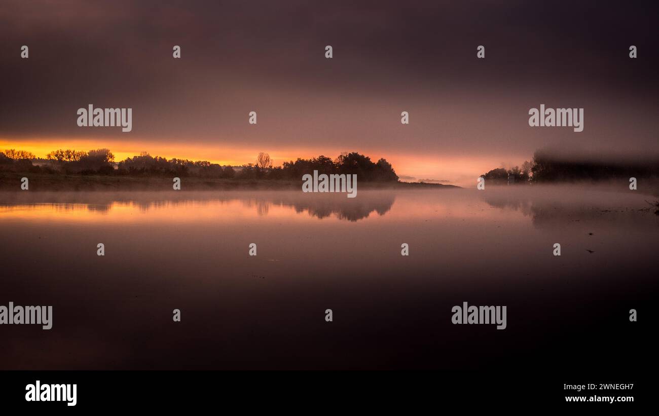 Friedlicher Sonnenaufgang mit zarter nebeliger Atmosphäre über einem spiegelnden Gewässer, Rhein Main Donau RMD Kanal Bamberg Stockfoto