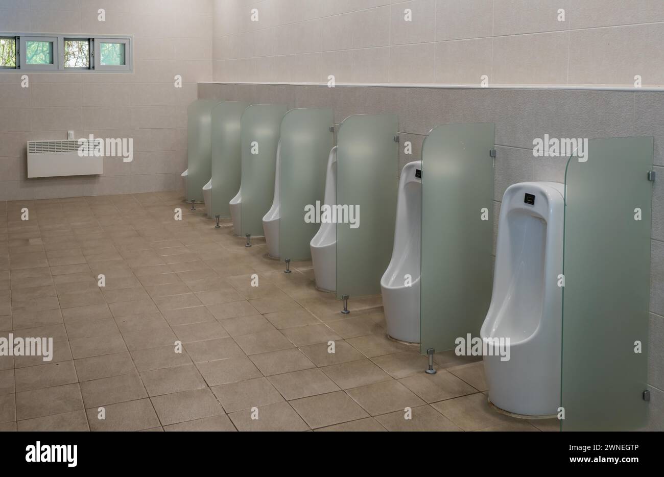 Reihe von Urinalen getrennt durch mattierte Glasplatten in der öffentlichen Toilette der Männer in Südkorea Stockfoto