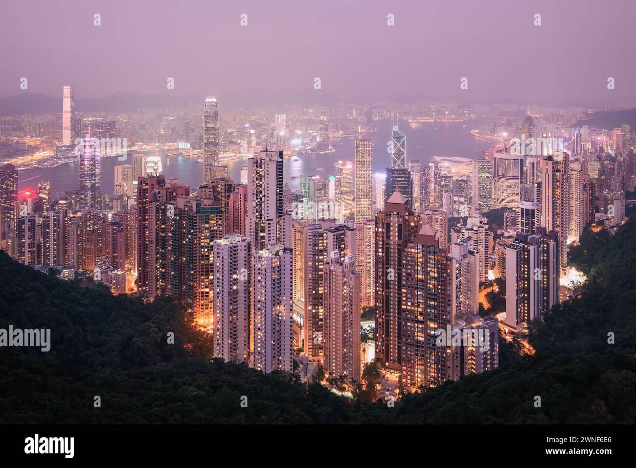 Die urbane Skyline von Hongkong mit hohen Wolkenkratzern in der stimmungsvollen Abenddämmerung. Stockfoto