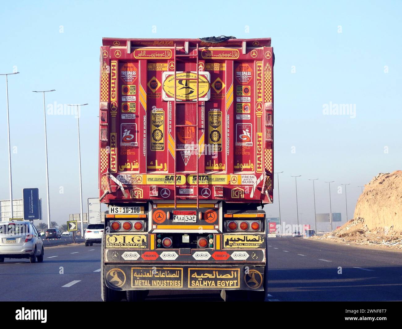 Kairo, Ägypten, 16. Dezember 2023: Tieflader-Lkw-Großfahrzeug mit einem Stahlcontainer, in Kairo Suez spezifische Spur, Versand- und Lieferservice Stockfoto