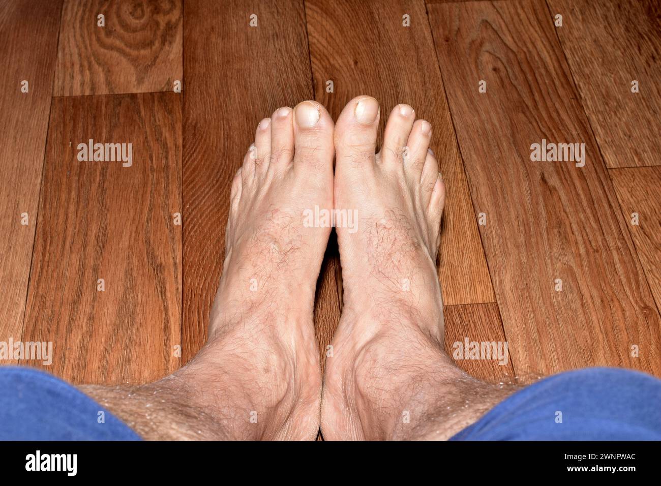 Blick von oben auf männliche Beine, die Füße sind miteinander verbunden und stehen auf dem Boden. Stockfoto