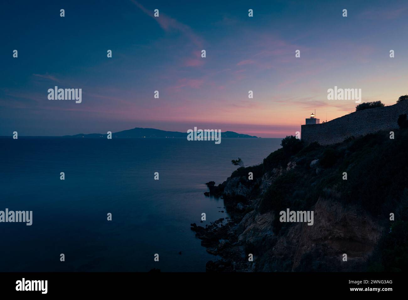 Talamone Leuchtturm vor dem Meer und Monte Argentario in der Dämmerung, Toskana, Italien Stockfoto