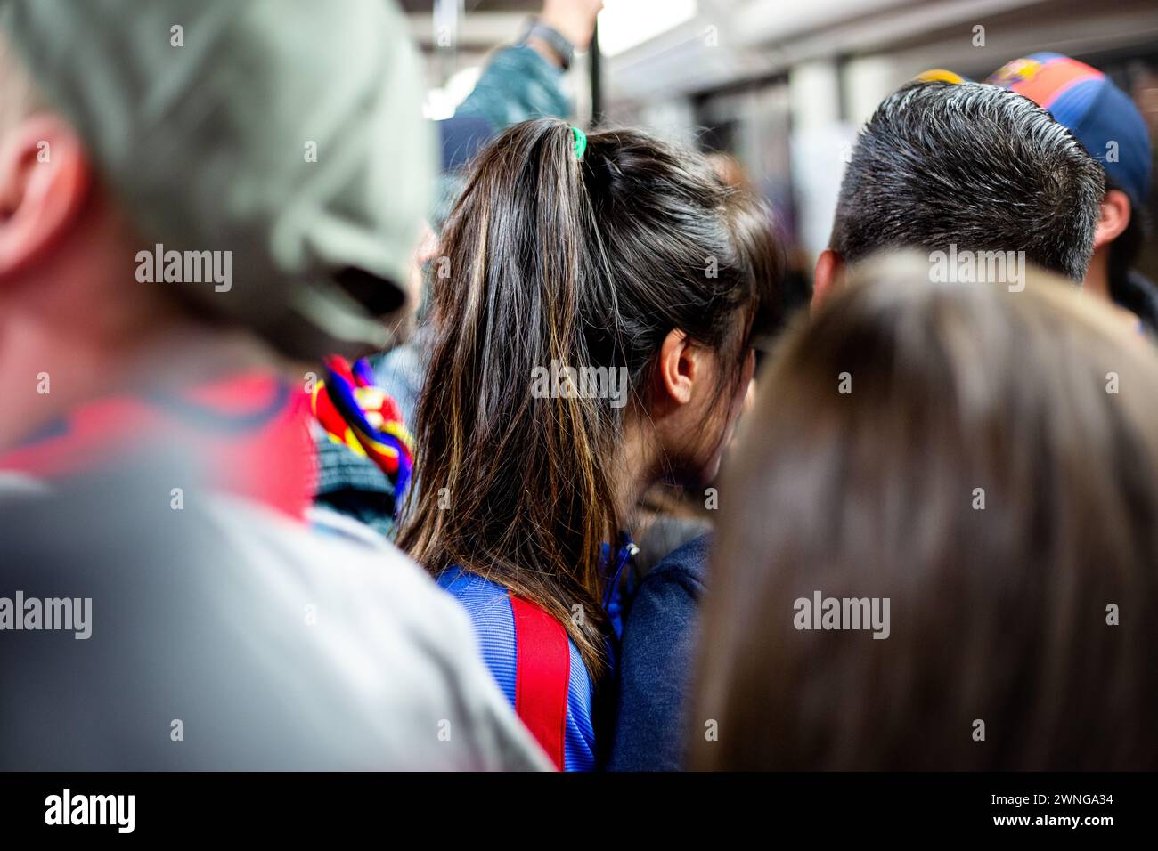 ÖFFENTLICHE VERKEHRSMITTEL, METRO, FANS, BARCELONA FC, 2019: Frau mit langen Haaren und Barca Top. Nach einem Spiel in Barcelona drängen sich die Fans in die U-Bahn. Durchnässte Barcelona-Fans gewinnen bei sintflutartigen Regenfällen leicht gegen einen Titelrivalen. Foto: Rob Watkins. Barcelona FC spielte Sevilla FC am 5. April 2017 im Camp Nou in Barcelona und Barca gewann das Spiel 3-0 mit drei Toren in den ersten 33 Minuten. Das ganze Spiel wurde in der Sintflut des heftigen Frühlingsregens gespielt. Stockfoto