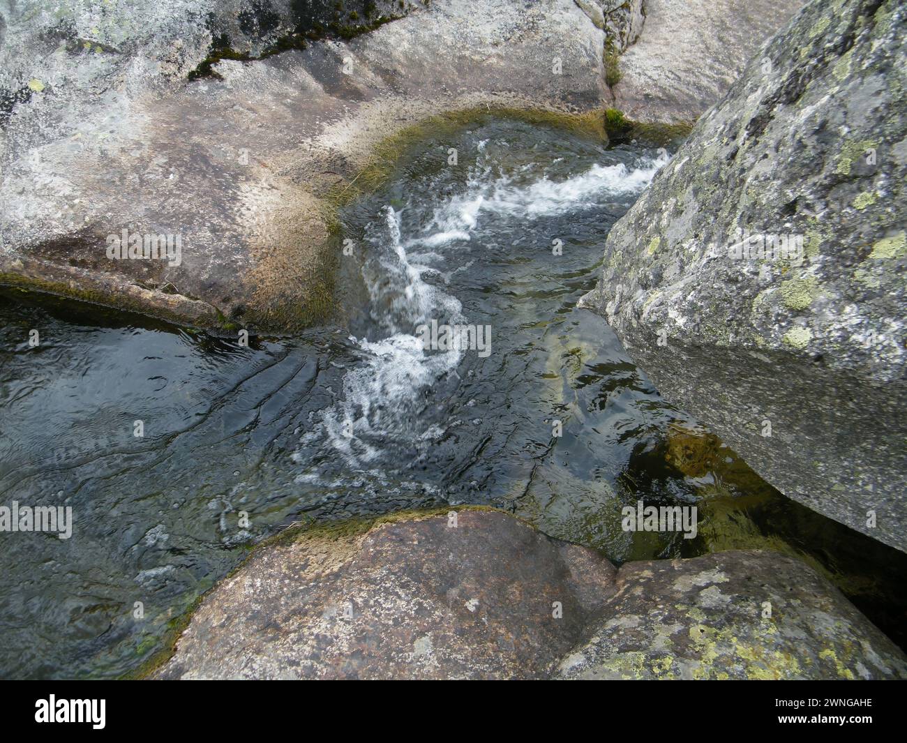 Um riacho de água fluindo através das rochas Stockfoto