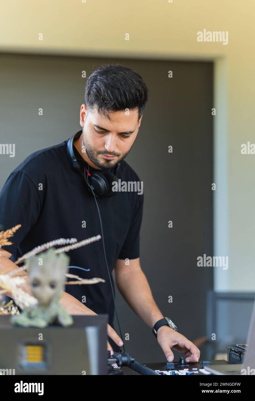 Der junge DJ konzentrierte sich auf seine Mischkonsole, während er dem Rhythmus der Party folgte. Stockfoto