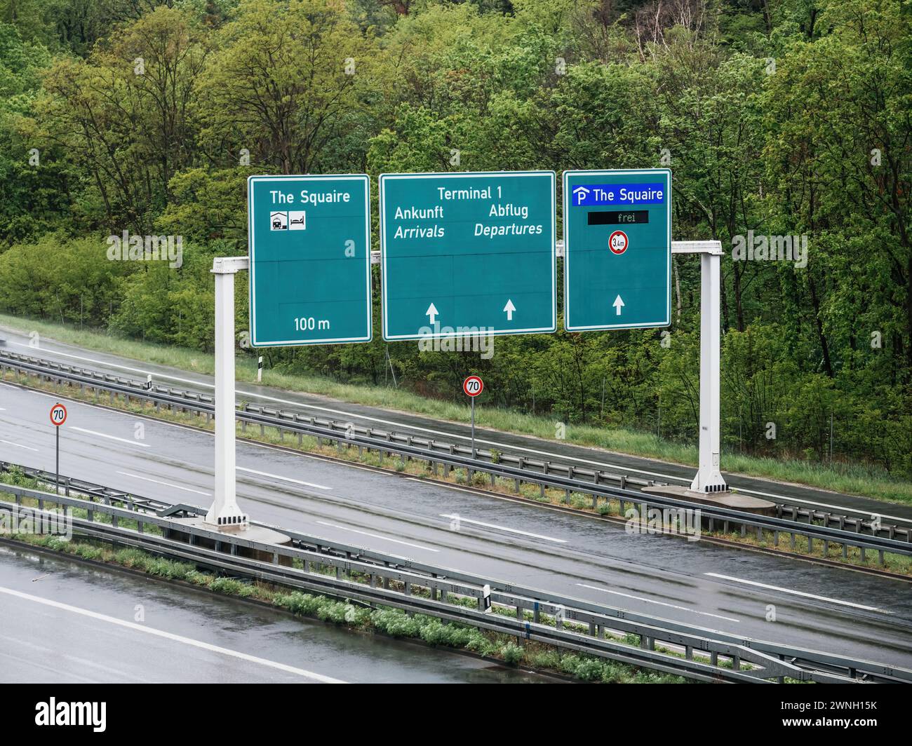 Aus der Vogelperspektive eines Richtungsschilds über der deutschen Autobahn, das Reisende zu Zielen wie dem Squaire, Ankunft und Abflug am Terminal 1 führt, um eine reibungslose Navigation für Autofahrer zu gewährleisten. 70 km/h Geschwindigkeitsbegrenzung Stockfoto