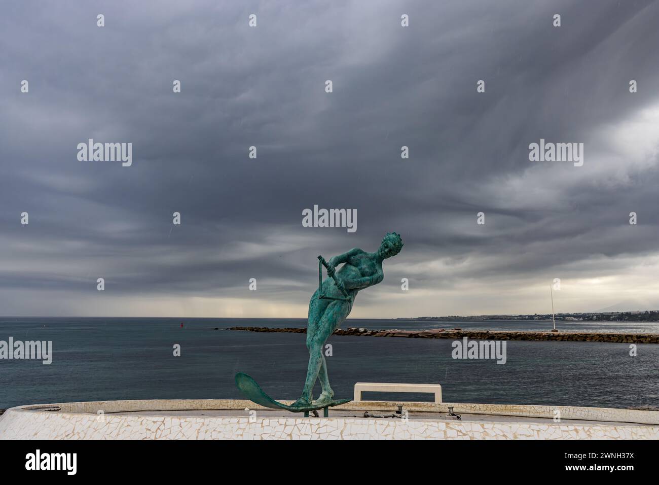 Marbella, „La Venus“ una escultura de bronce que repräsenta a una mujer Practice ando esquí acuático. El mar al fondo y el cielo tormentoso. España Stockfoto