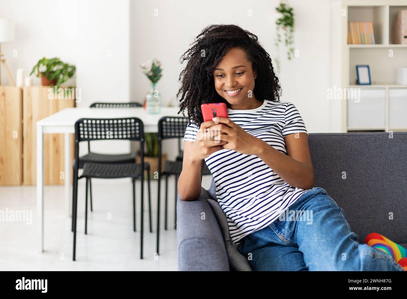 Lächelnde junge afroamerikanerin, die auf dem Sofa sitzt. Stockfoto