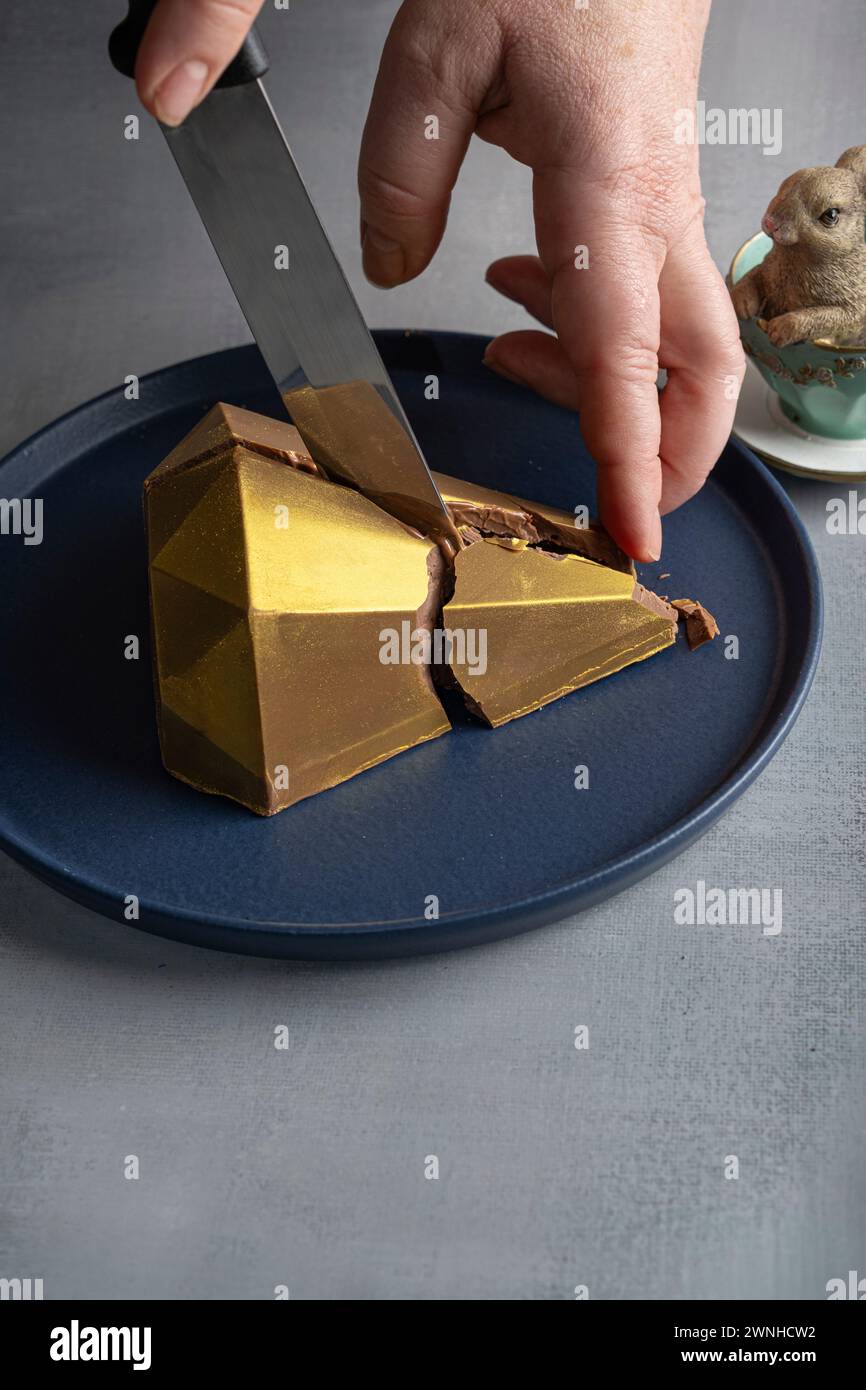 Low Key Belgische Milchschokolade Osterei in goldener Vorderform 9. Stockfoto