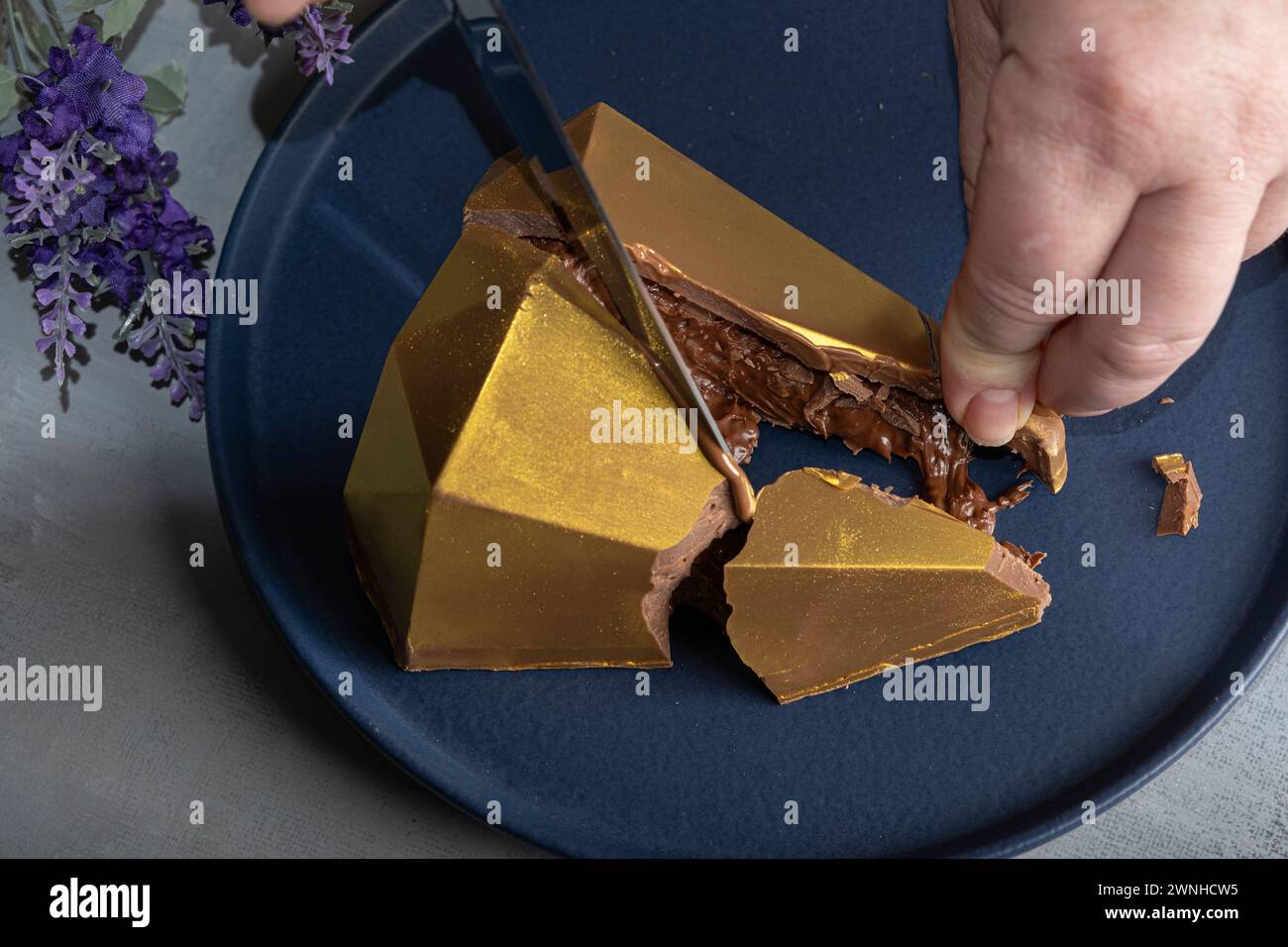 Low Key Belgische Milchschokolade Osterei in goldener Vorderform 10. Stockfoto