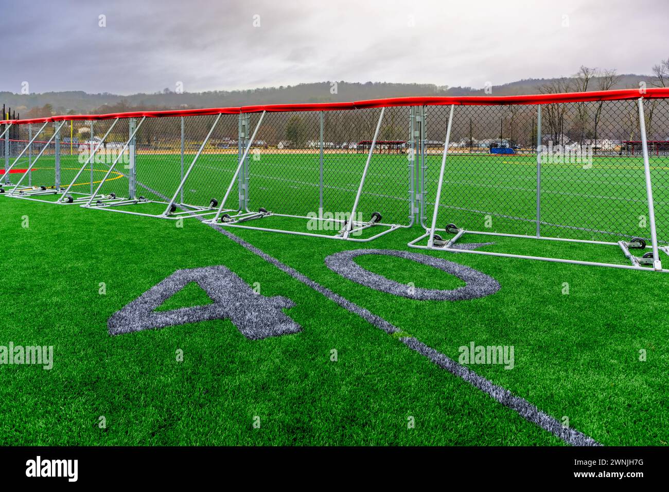 Kunstrasen Fußball mit 40-Yard-Linien und Blocknummern in Grau mit einem tragbaren Baseball-Außenfeldzaun. Stockfoto