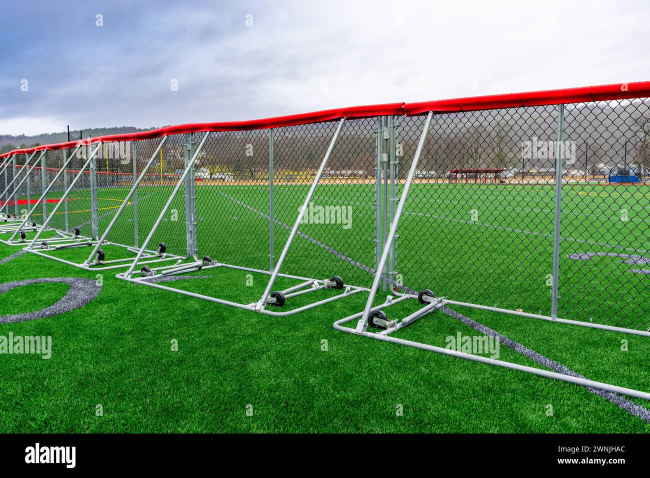 Kunstrasen Fußball mit 40-Yard-Linien und Blocknummern in Grau mit einem tragbaren Baseball-Außenfeldzaun. Stockfoto