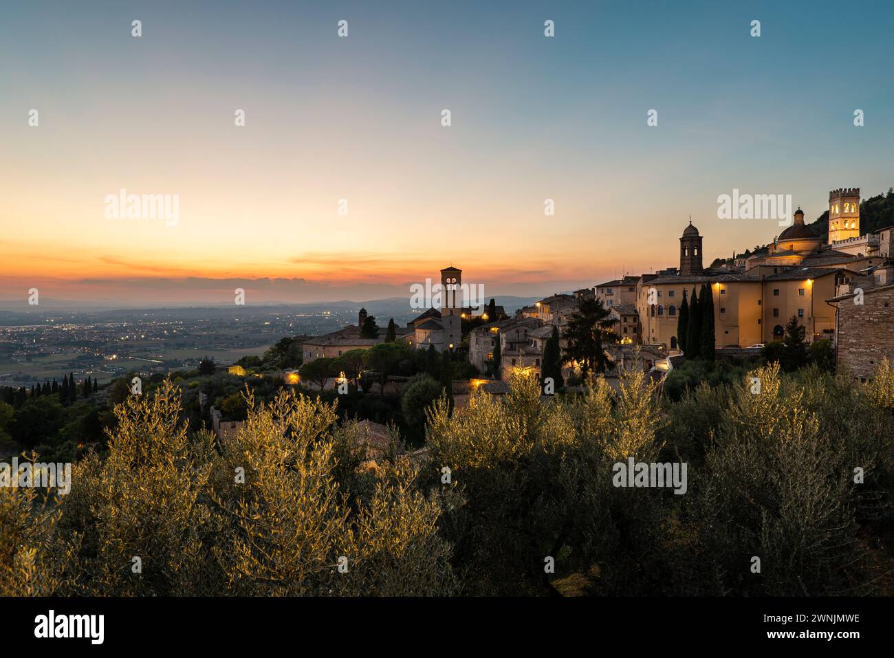 Blick vom Piazza Santa Chiara auf den goldenen Sonnenuntergang über das Umbra-Tal und die Altstadt von Assisi, Umbrien, Italien Stockfoto