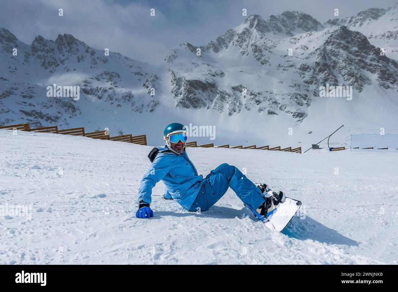 Männlicher Snowboarder sitzt auf einer Skipiste in Ordino Arcalis, Andorra Stockfoto