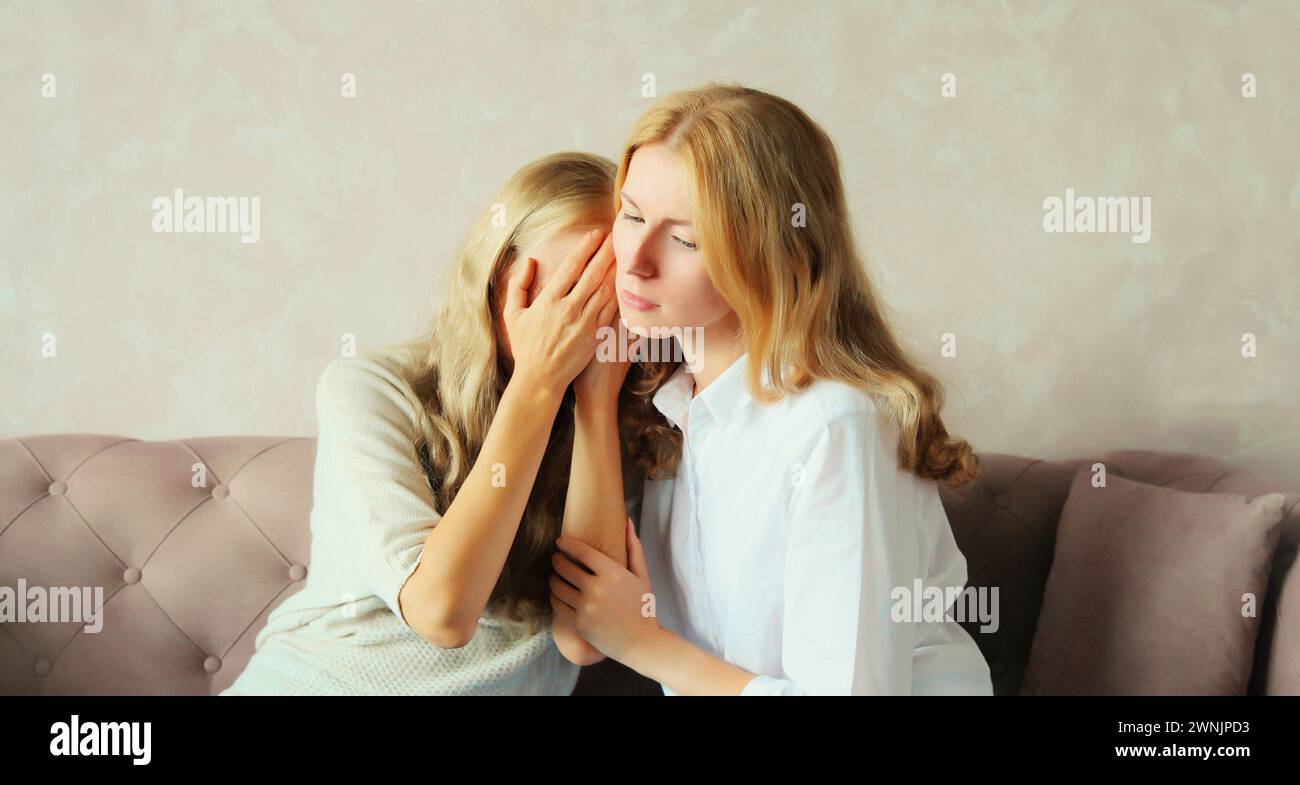 Verärgert beleidigte kaukasische Mutter mittleren Alters oder Schwester und Erwachsene Tochter zusammen auf der Couch zu Hause sitzen Stockfoto