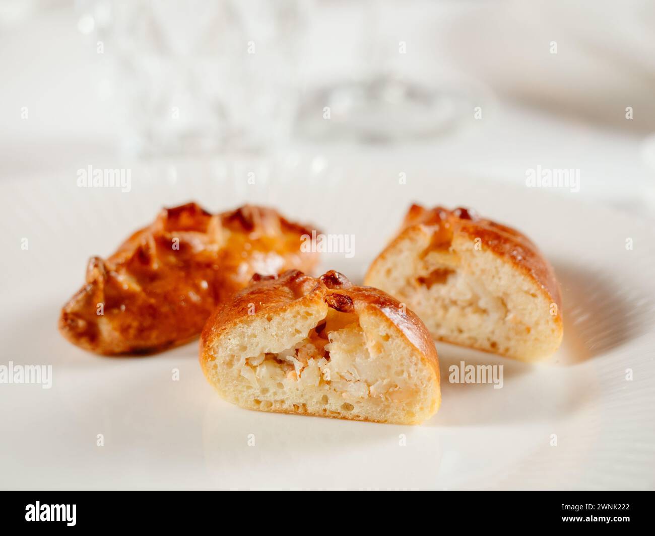 Kleine russische Torten mit gehacktem Lachsfisch russischer Piroschki. Gekochter Thunfisch handportionierte Torten oder Empanadas, halbiert auf weißer Platte in eleganter Form Stockfoto