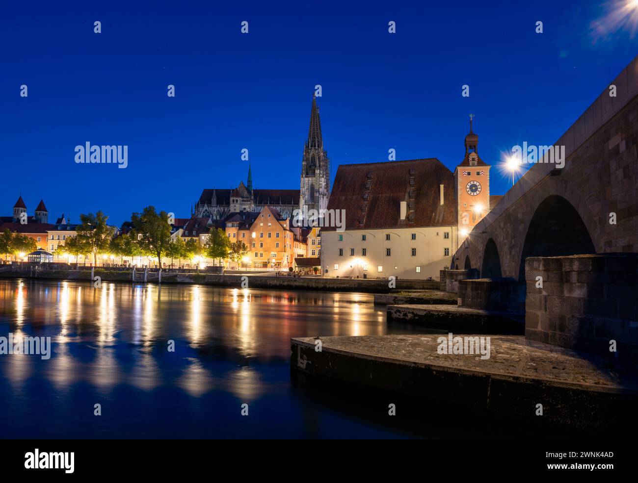 Regensburger Stadtbild während der blauen Stunde mit Lichtreflexen in der Donau Stockfoto