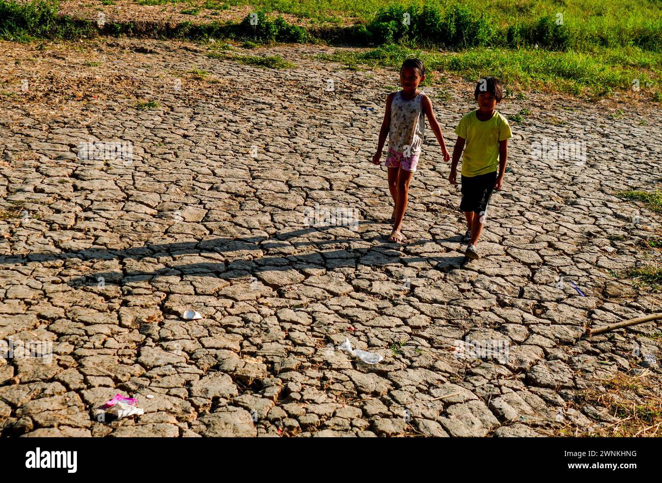 Quezon City, Philippinen. März 2024. Kinderspaziergänge auf einem ausgetrockneten Reisfeld in Brgy. Bagong Silangan erlebt derzeit eine Dürre inmitten des El-Niño-Phänomens. (Foto von EDD Castro/Pacific Press) Credit: Pacific Press Media Production Corp./Alamy Live News Stockfoto