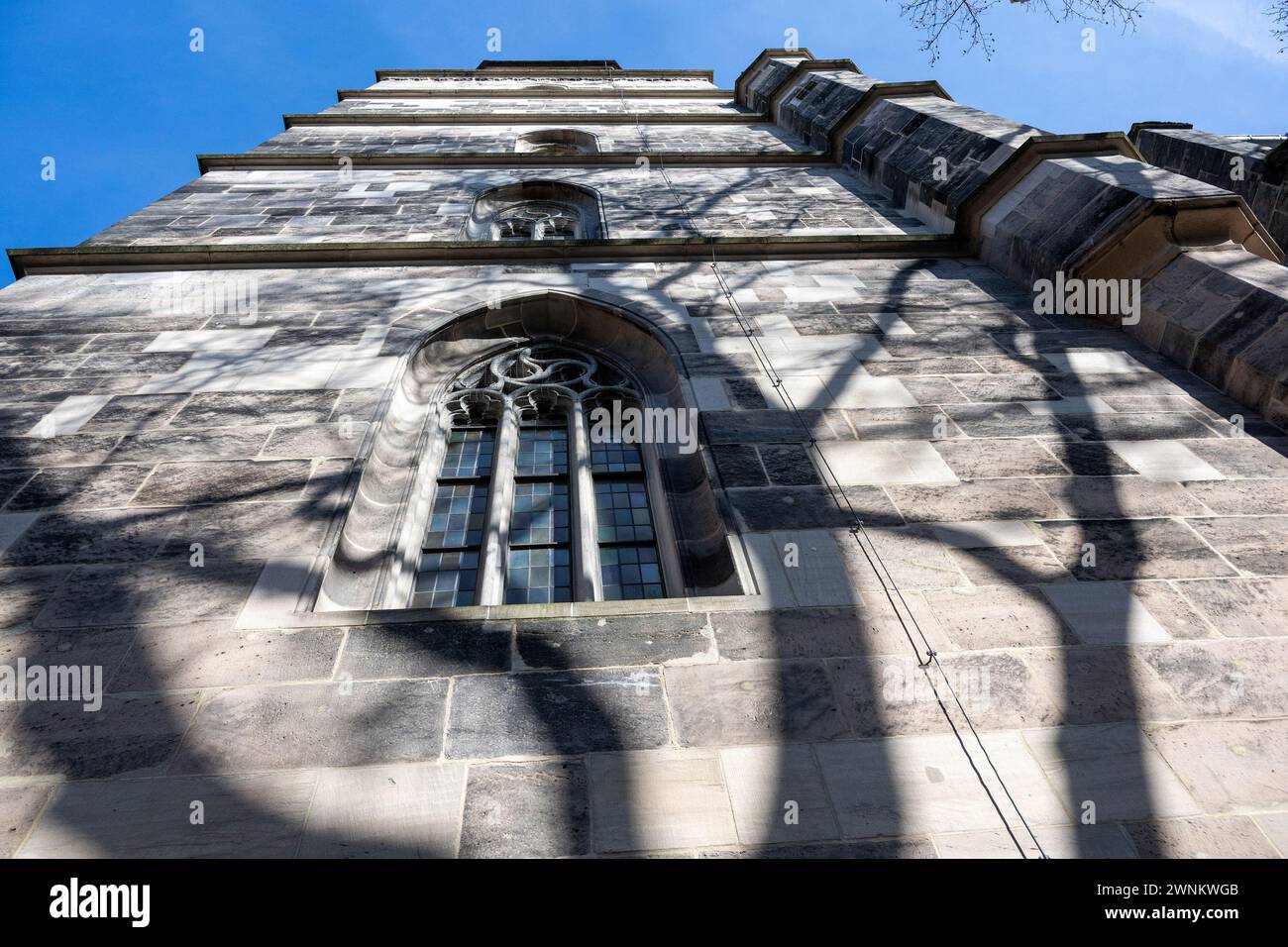 Coburg, Deutschland. März 2024. Ein blühender Baum wirft seinen Schatten über die evangelisch-lutherische Stadtkirche St. Moriz in Coburg. Bei frühlingshaften Temperaturen wird in Coburgs ältester Kirche die Hälfte der zweiten Vesperkiche in Coburg gefeiert. Quelle: Pia Bayer/dpa/Alamy Live News Stockfoto