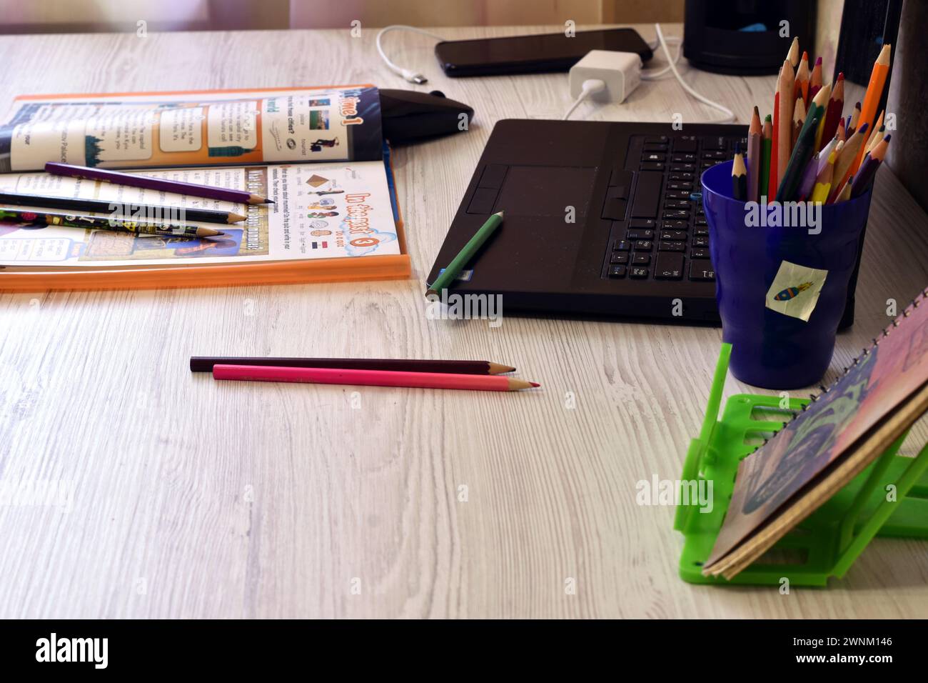 Das Bild zeigt ein Chaos auf dem Tisch im Büro, Bleistifte, einen Laptop, ein Magazin. Stockfoto