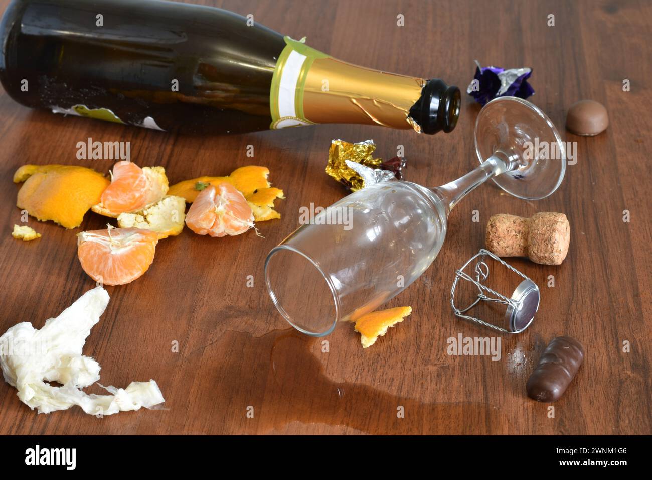 Nach einem lustigen Urlaub blieben eine Flasche, ein Glas mit verschüttetem Wein und eine Schale von Mandarinen auf dem Tisch. Stockfoto