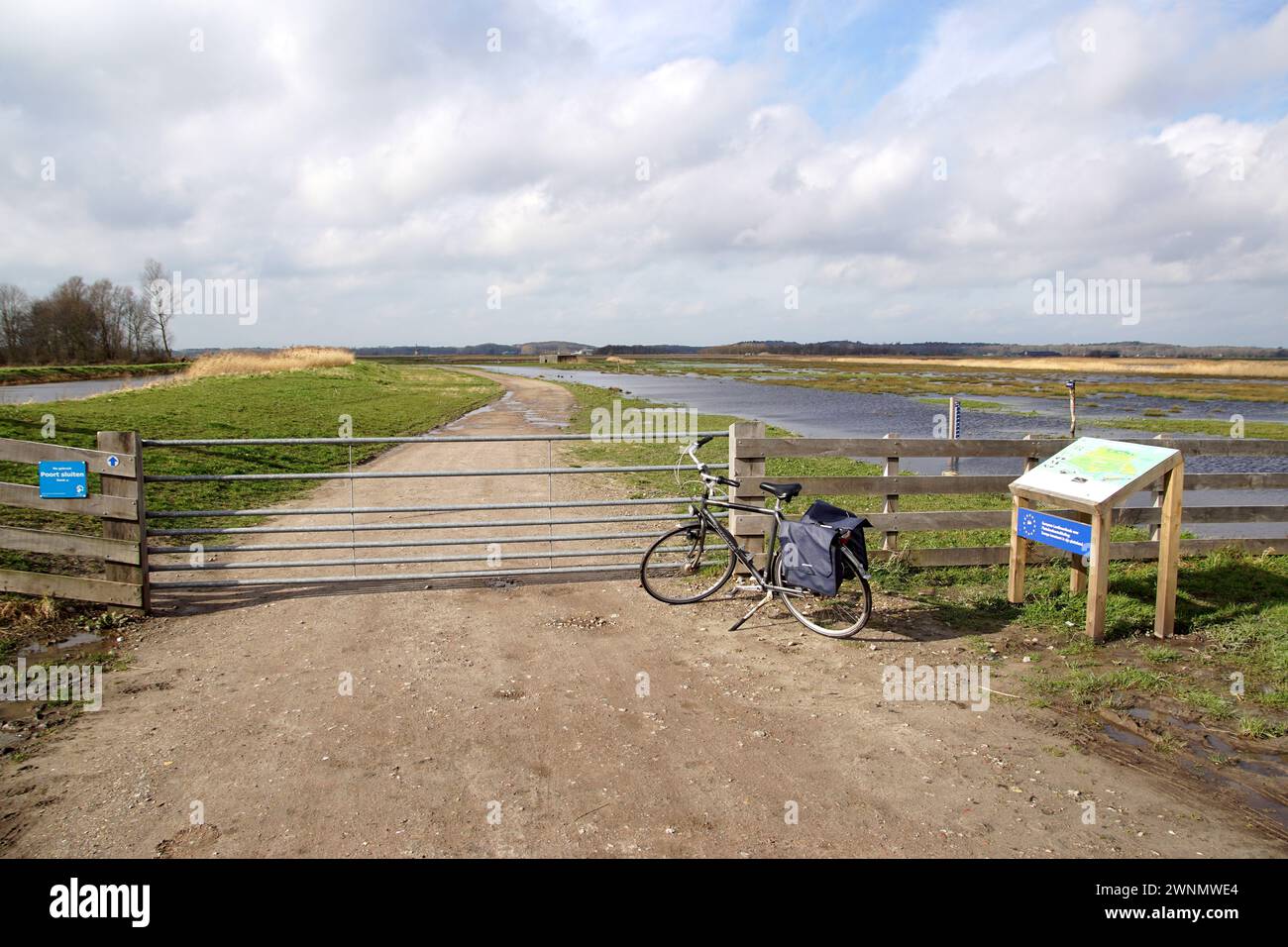 Polderwasserspeicher bei sehr hohem Regenwasser. Teilweise überflutet, um die niedrigen Polder in der Nachbarschaft zu schützen. Schotterweg, Zaun, Tor. Graben, Wiese Stockfoto