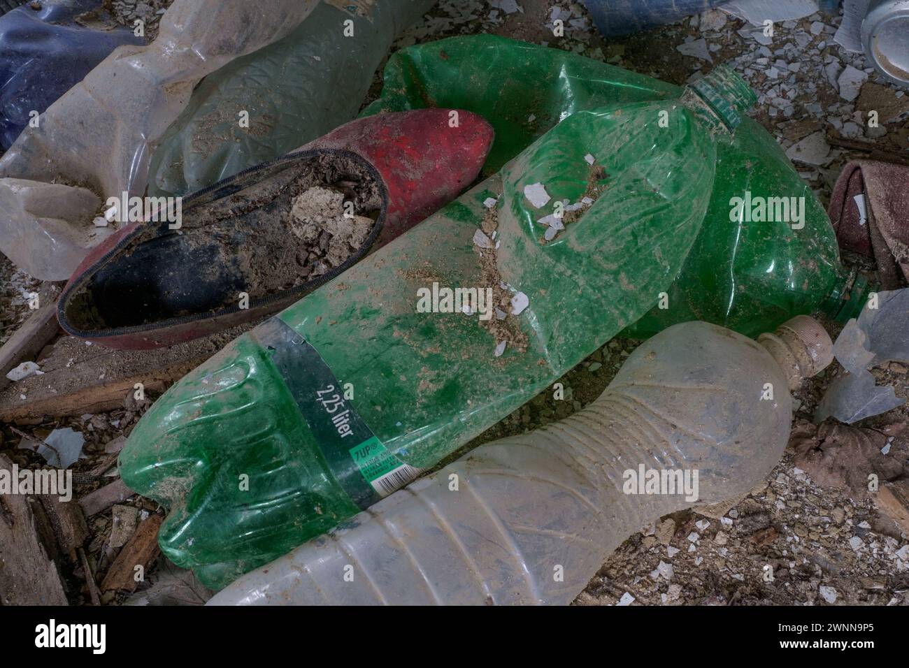 Entsorgte rote Schuhe zwischen Plastikflaschen im verlassenen Wrack des zerbröckelnden, einstürzenden Landhauses ungarn Stockfoto