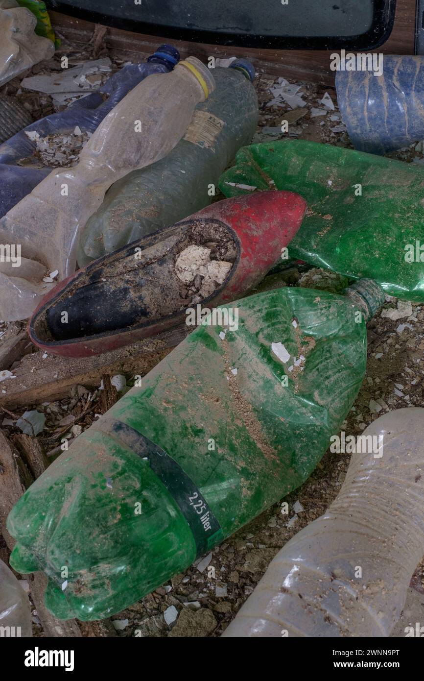 Entsorgte rote Schuhe zwischen Plastikflaschen im verlassenen Wrack des zerbröckelnden, einstürzenden Landhauses ungarn Stockfoto