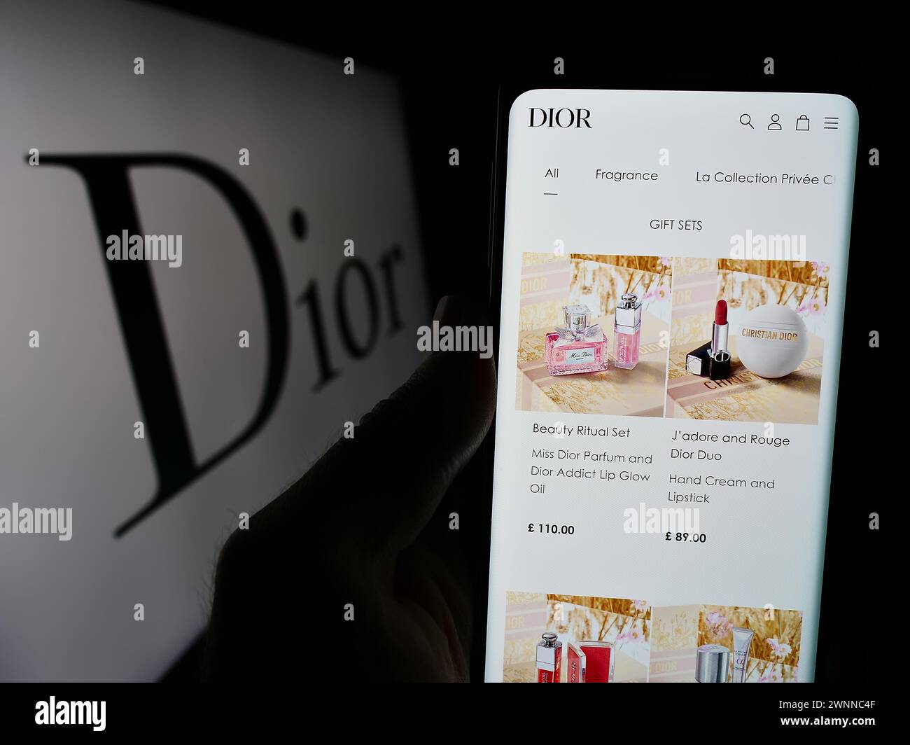 Person, die ein Handy hält, mit der Webseite des französischen Luxusmodeunternehmens Christian Dior SE vor dem Logo. Konzentrieren Sie sich auf die Mitte des Telefondisplays. Stockfoto