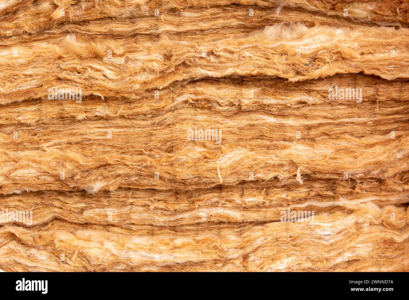 Nahaufnahme der Mineralwolle-Füllung, die als Isolierung in der Wand verwendet wird. Gelbe Mineralwolle mit sichtbarer Textur. Stockfoto