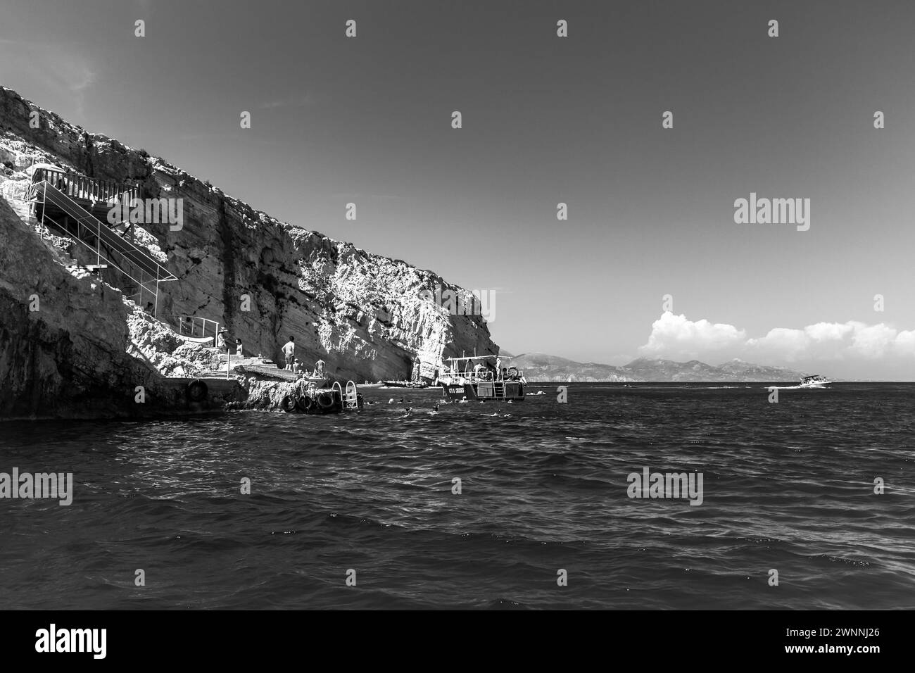 Zakynthos, Griechenland - 20. August 2016: Schwarzweiß-Landschaftsfoto mit Felsen der griechischen Insel Zakynthos. Die Leute sind auf der Blauen Höhle Bootsfahrt Emban Stockfoto