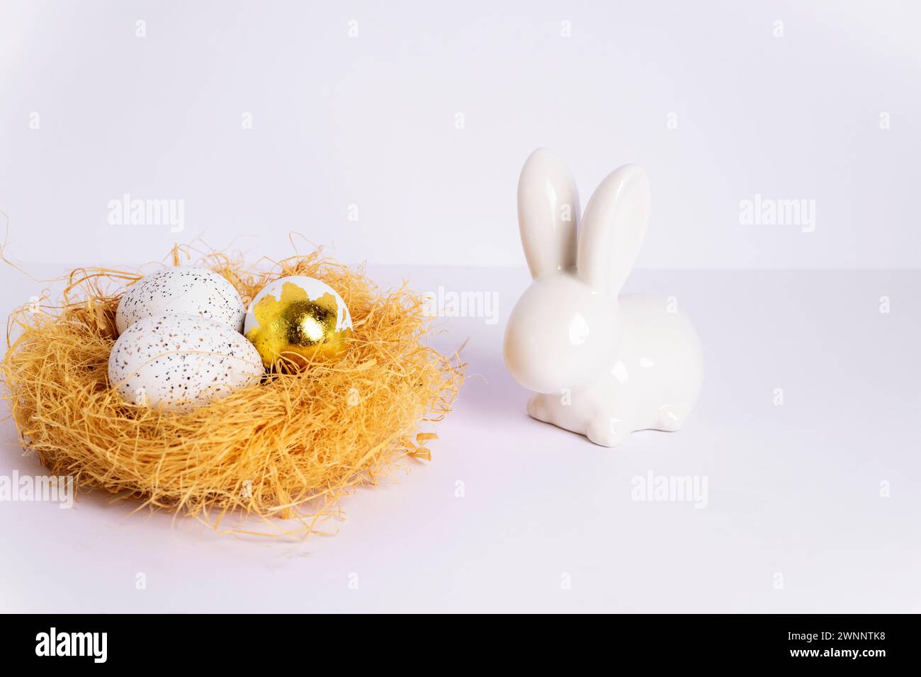 Nest mit Ostereiern und Häschen auf weißem Tisch. Nahaufnahme. Stockfoto