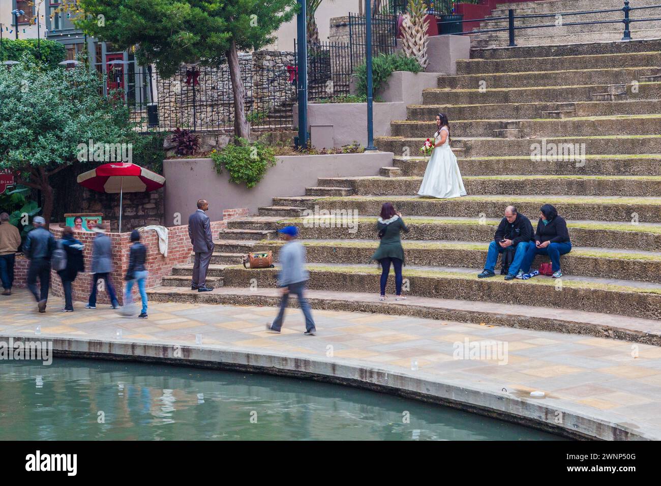 Die Braut wird auf den grasbewachsenen Sitzplätzen des Arneson River Theater am River Walk in der Innenstadt von San Antonio, Texas, fotografiert Stockfoto