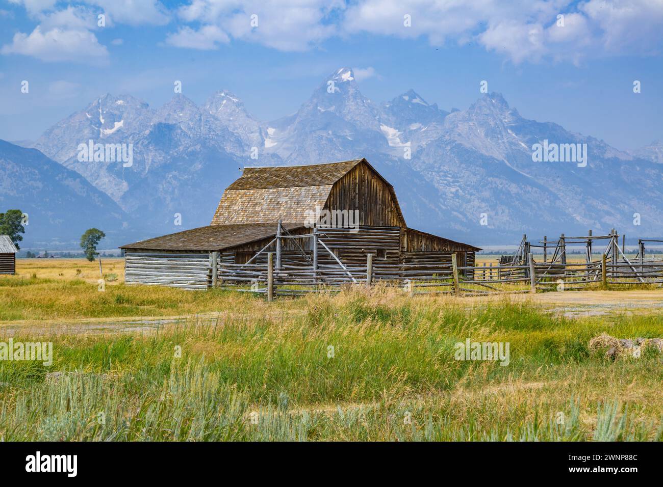 Die Gipfel der Grand Tetons ragen hinter der John Moulton Barn in der Mormon Row im Historic District des Grand Teton National Park in Wyoming auf Stockfoto