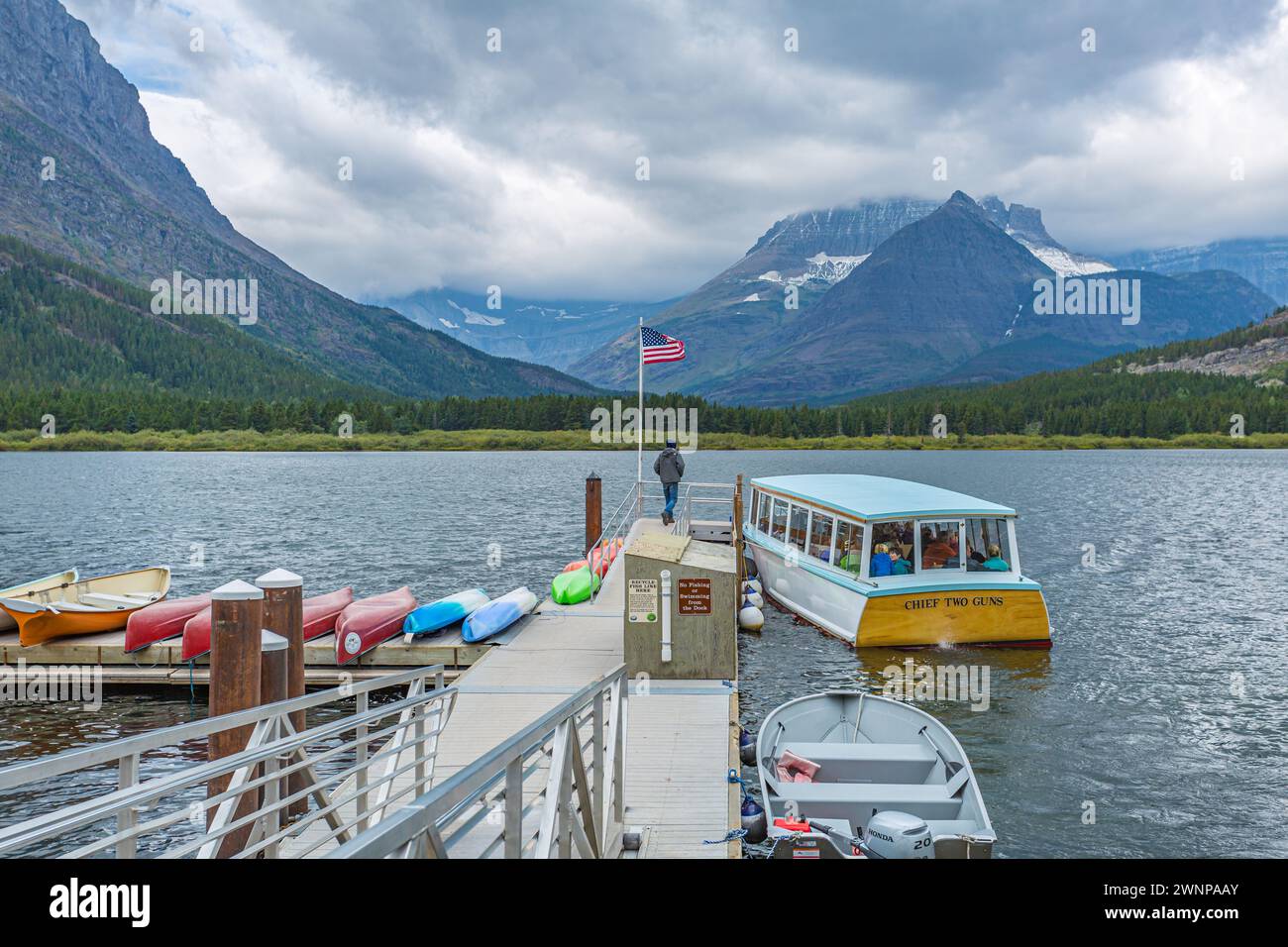 Das Chief Two Guns Tour Boot nähert sich dem schwimmenden Dock am Swiftcurrent Lake im Many Glacier Hotel im Glacier National Park, Montana Stockfoto