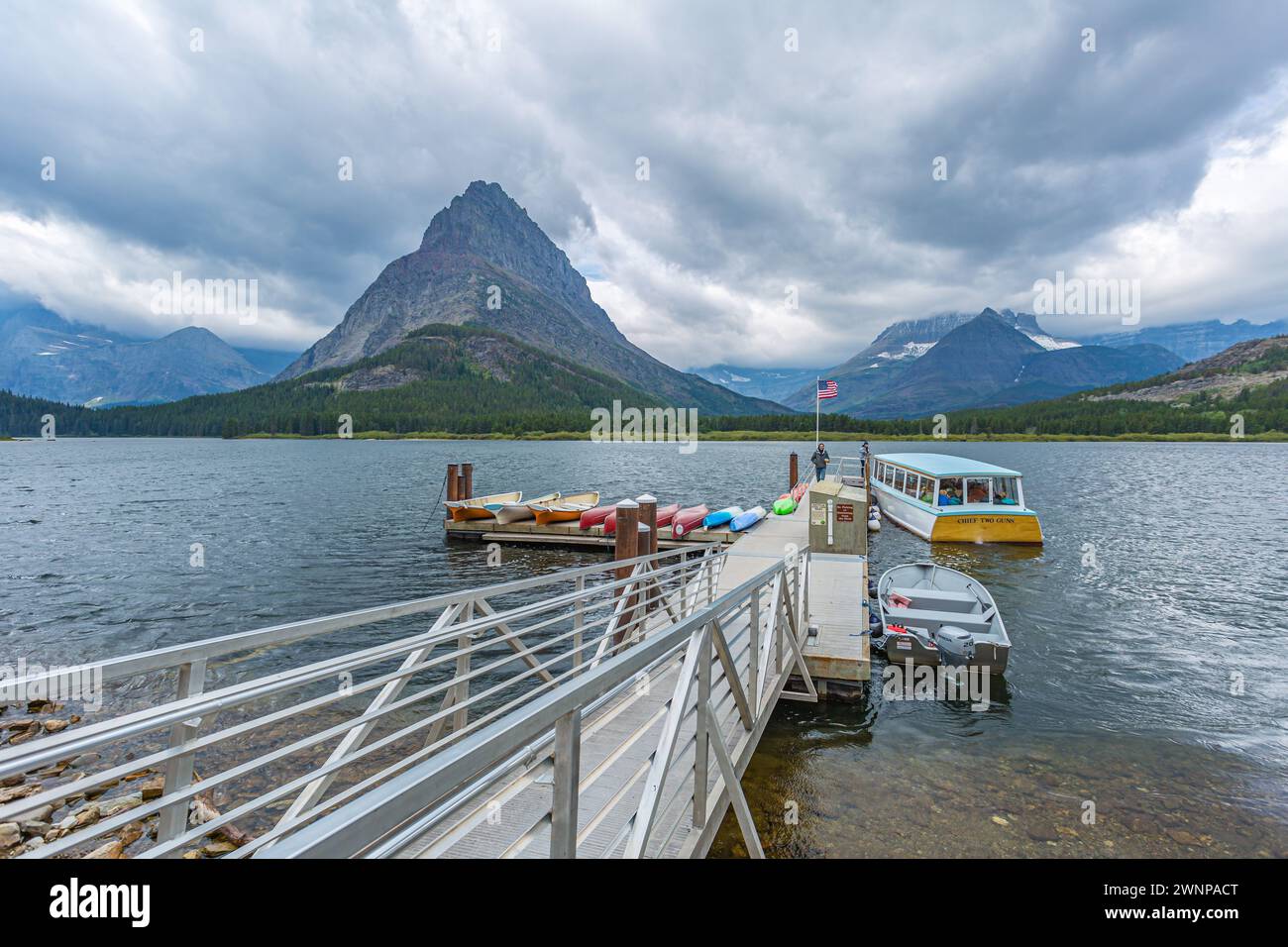 Das Chief Two Guns Tour Boot nähert sich dem schwimmenden Dock am Swiftcurrent Lake im Many Glacier Hotel im Glacier National Park, Montana Stockfoto