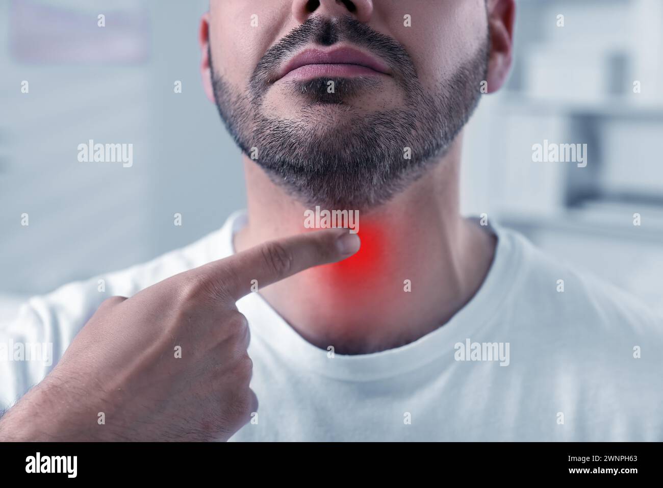 Endokrines System. Ein Mann, der die Schilddrüse selbst untersucht, in geschlossenen Räumen Stockfoto