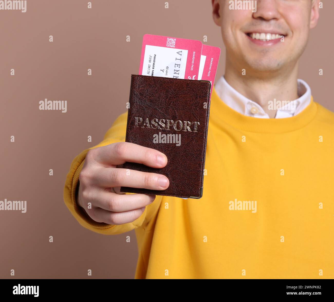 Lächelnder Mann mit Pass und Tickets auf beigefarbenem Hintergrund, Nahaufnahme Stockfoto