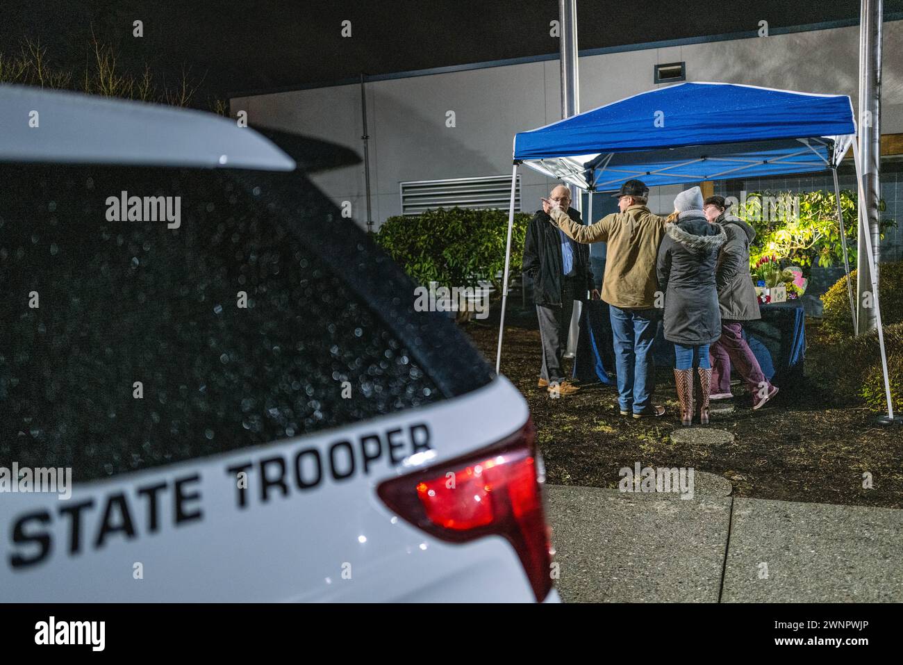 Marysville, Usa. März 2024. Die Familie von Trooper Christopher Gadd steht in einer düsteren Umgebung neben dem sich erweiternden Denkmal, das zu seinen Ehren im Hauptquartier der Washington State Patrol in Marysville errichtet wurde. Die Kollision, die in der Nähe der 136th Street Northeast kurz vor 3 Uhr morgens stattfand, löste eine sofortige Reaktion der Sheriffs von Snohomish County aus. Der Soldat, genannt Christopher Gadd, im Alter von 27 Jahren, erlag tragischerweise seinen Verletzungen am Tatort. Gadd, der 2,5 Jahre bei der Staatspatrouille gedient hatte, war in Marysville stationiert. Quelle: SOPA Images Limited/Alamy Live News Stockfoto