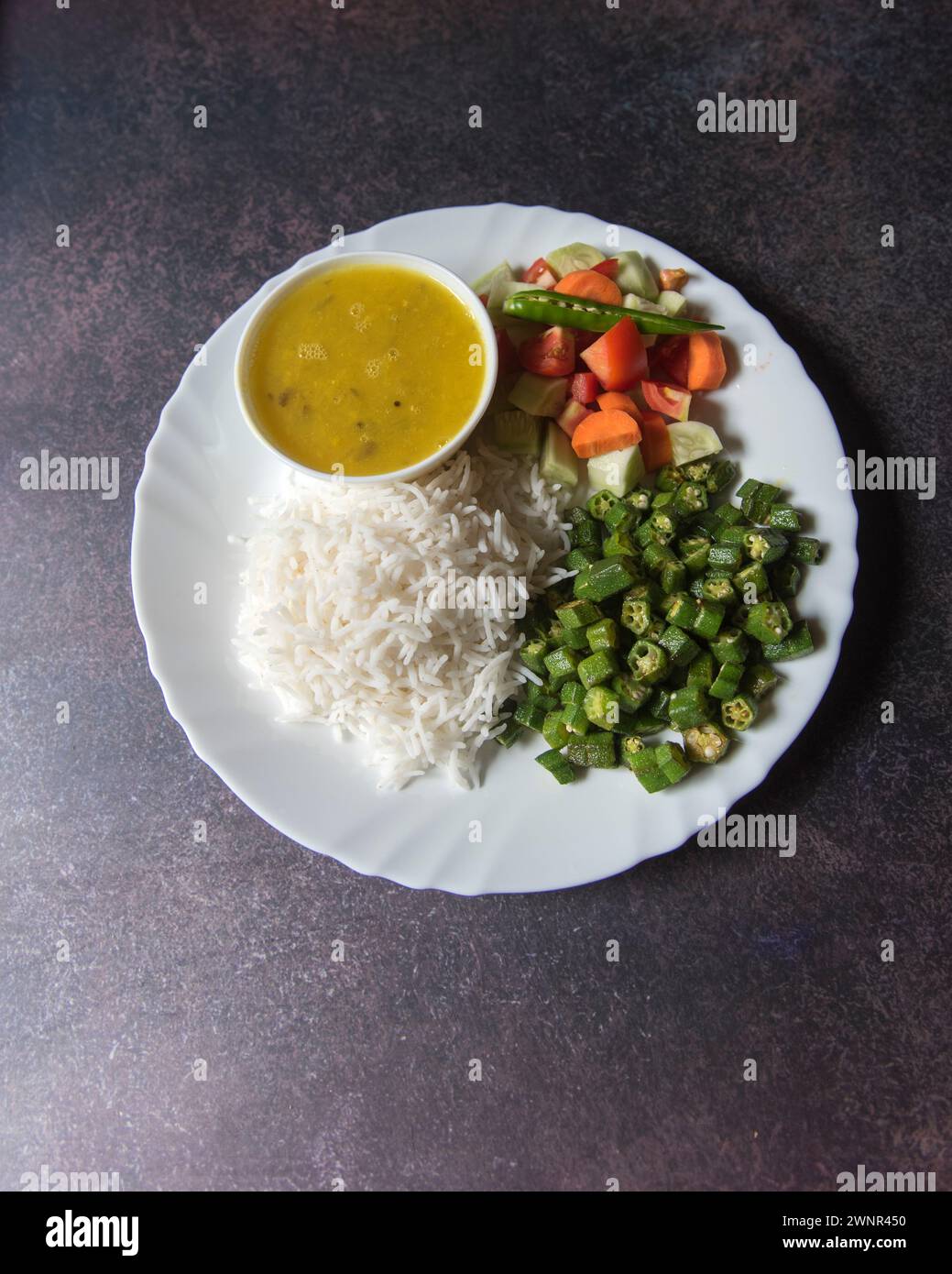 Blick von oben auf gesundes indisches Gemüse Reis, Dal, Gemüse und Salat serviert auf einem Teller. Stockfoto