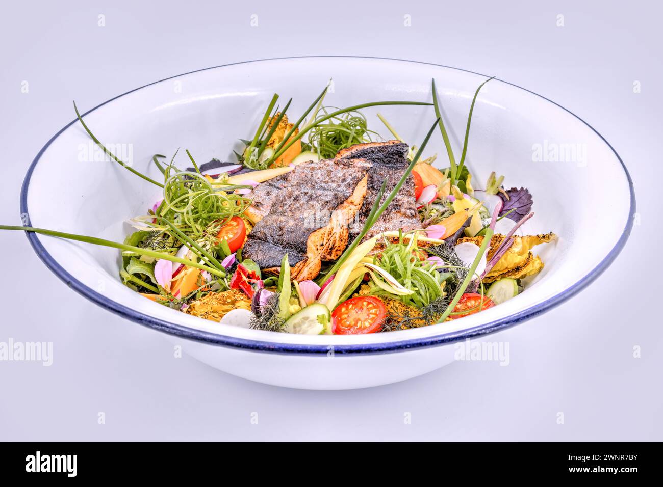 Frischer Gartensalat mit gegrillten Fischfilets in einer weißen Schüssel Stockfoto