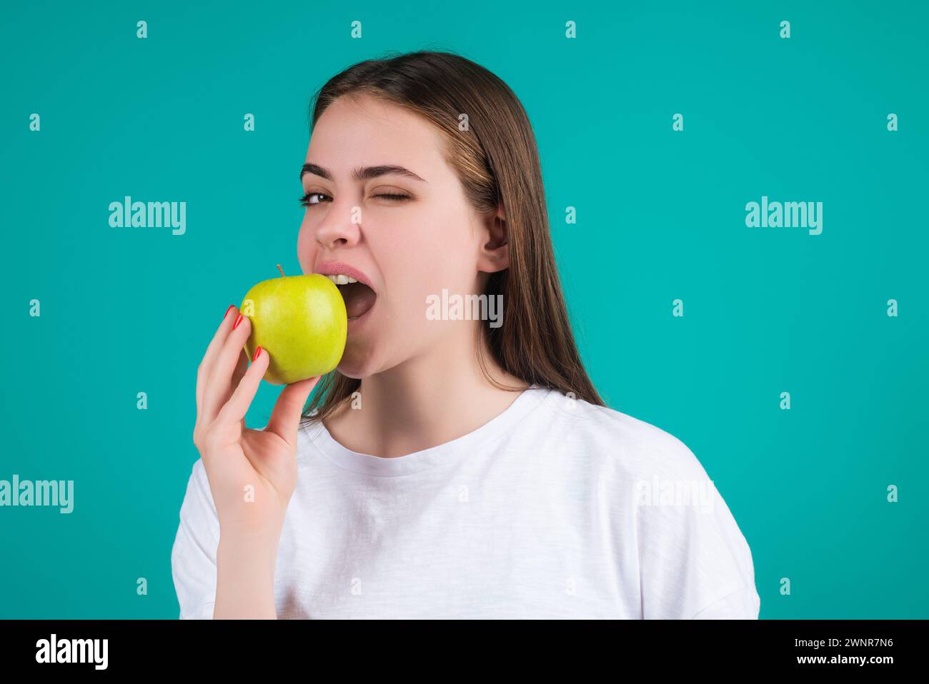 Junge Frau, die Apfel schlägt, gesunder Lebensstil. Mädchen haben ein frisches, grünes Apfelporträt auf grünem, isoliertem Hintergrund. Gesundes Essen. Obst für Stockfoto