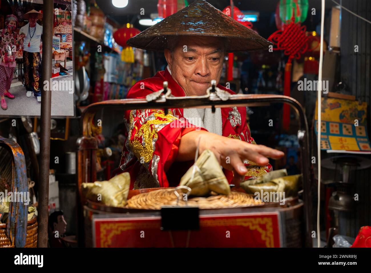 Thailand, 10. Februar 2024: Chakngeaw Chinese Village. Ein Verkäufer sucht nach einem Zongzi, einem klebrigen Reis mit herzhaften Füllungen in Bambusblättern. Stockfoto