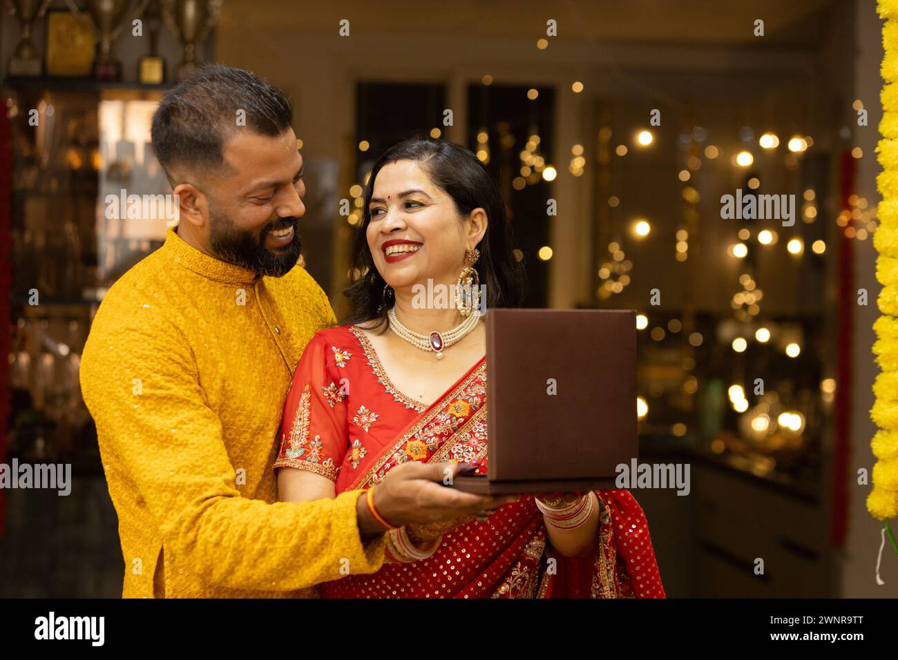 Der junge indische Ehemann schenkt ihrer Frau kostbaren Schmuck auf Diwali oder Hochzeitstag. Ehemann und Ehefrau tragen traditionelle Kleidung auf festiva Stockfoto