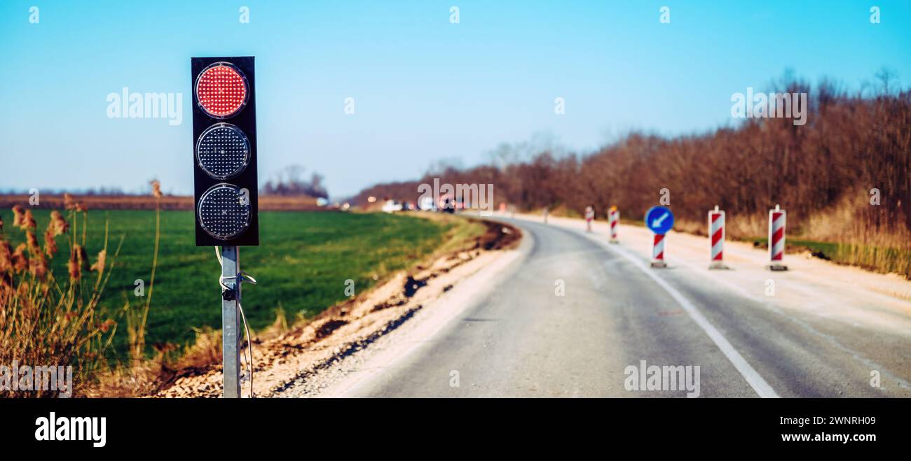Semaphorische Ampelsignalisierung bei Straßeninstandhaltung, rote Ampelkreuzung zur Verkehrsregulierung, selektiver Fokus Stockfoto