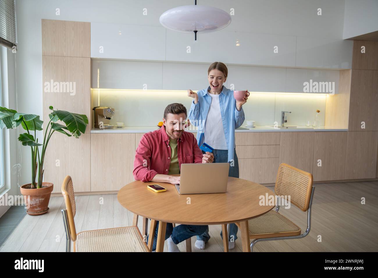 Ein enthusiastischer, glücklicher Mann und eine überglückte Frau schauen sich den Laptop an, wenn man den großen Geldgewinn ankündigt Stockfoto