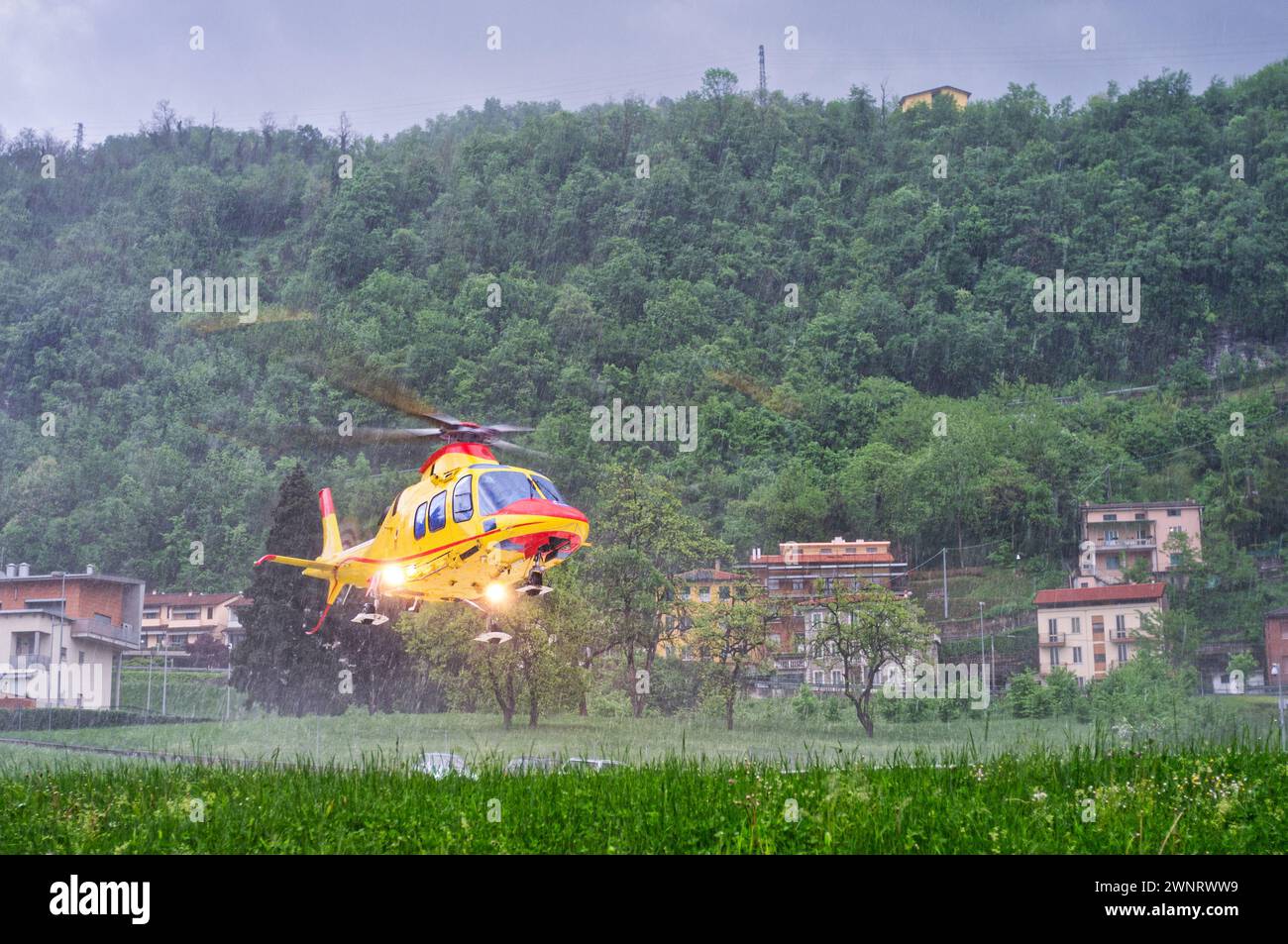 Helicopter emergency medical service taking off from a hospital helipad in heavy rain during a severe thunderstorm Stockfoto