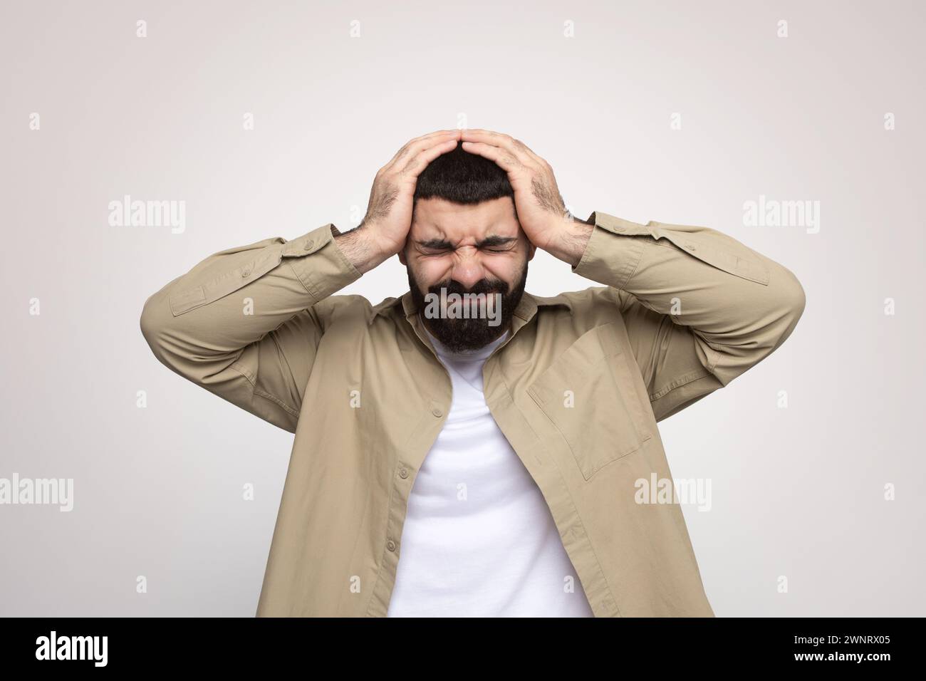 Ein gestresster Mann mit einem Bart, der frustriert und den Kopf in den Händen hält Stockfoto